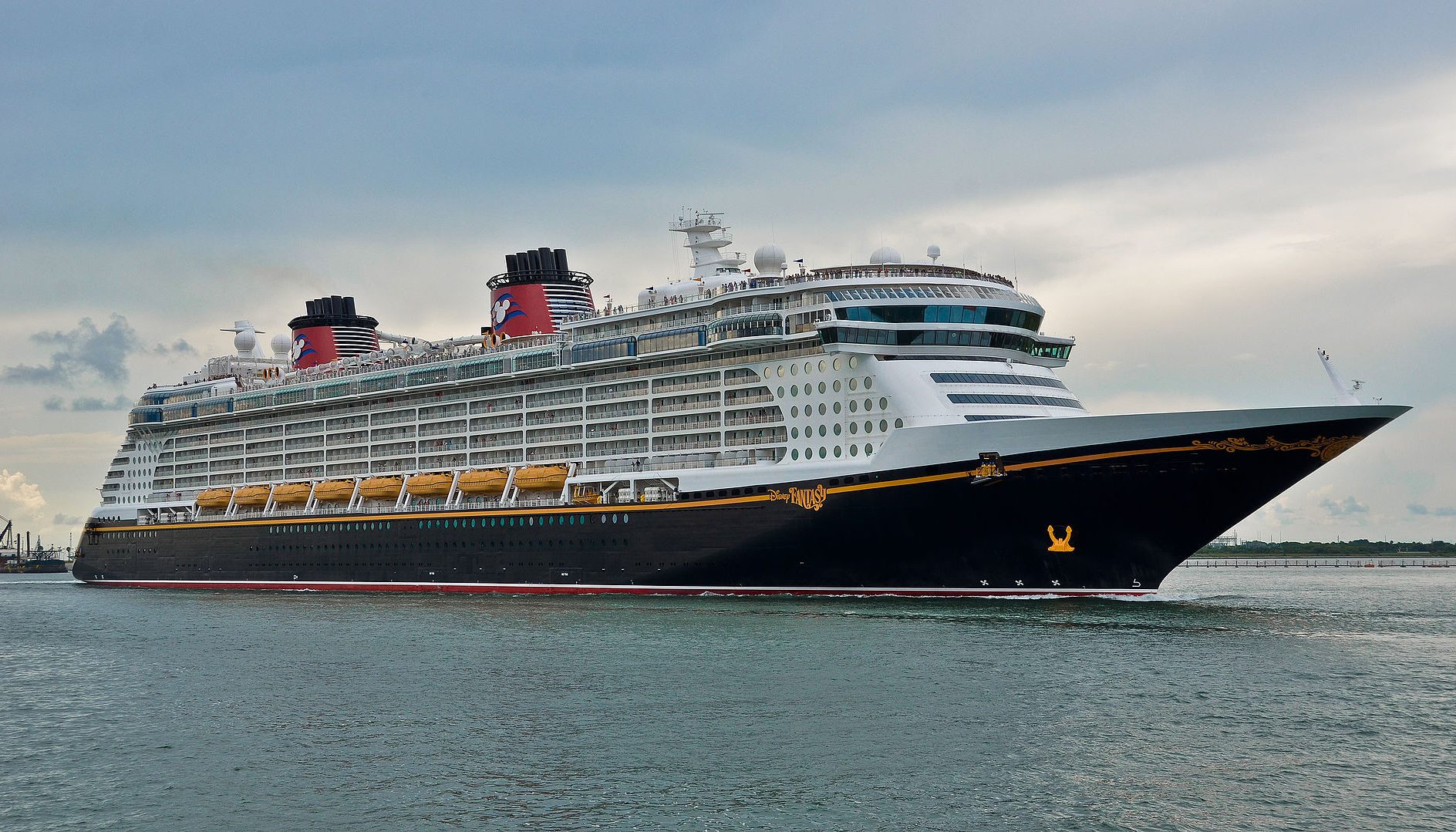 cruise ship gratuities cruise ship Large Disney cruise ship sailing in calm waters under a cloudy sky.