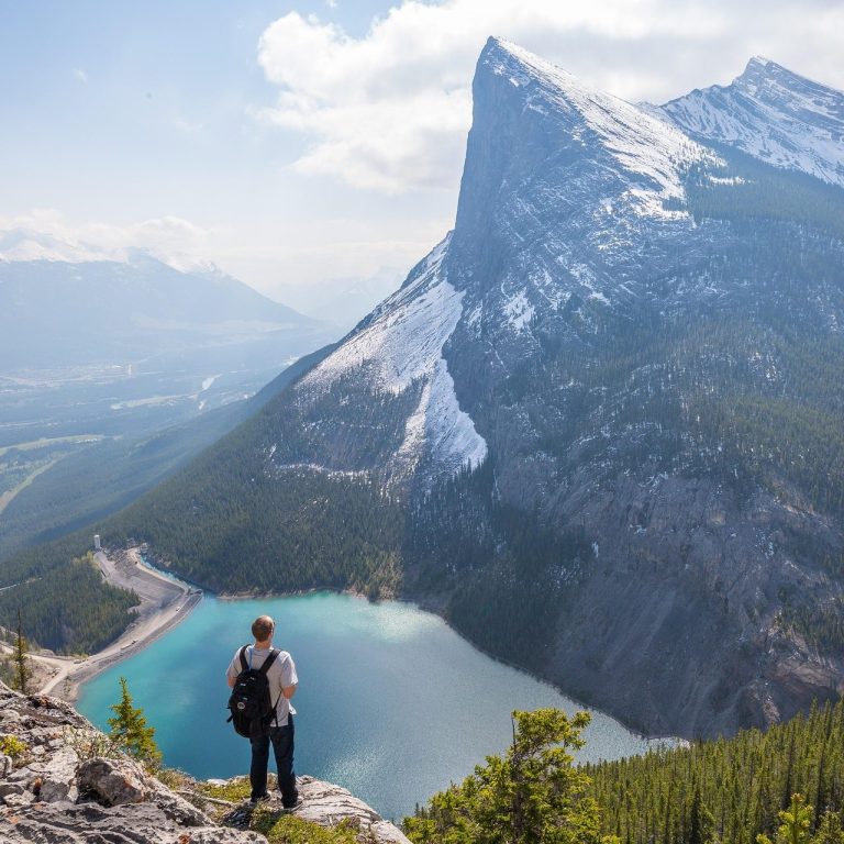 Backpacking Vacation Hiker overlooking a mountainous landscape with a turquoise lake below.