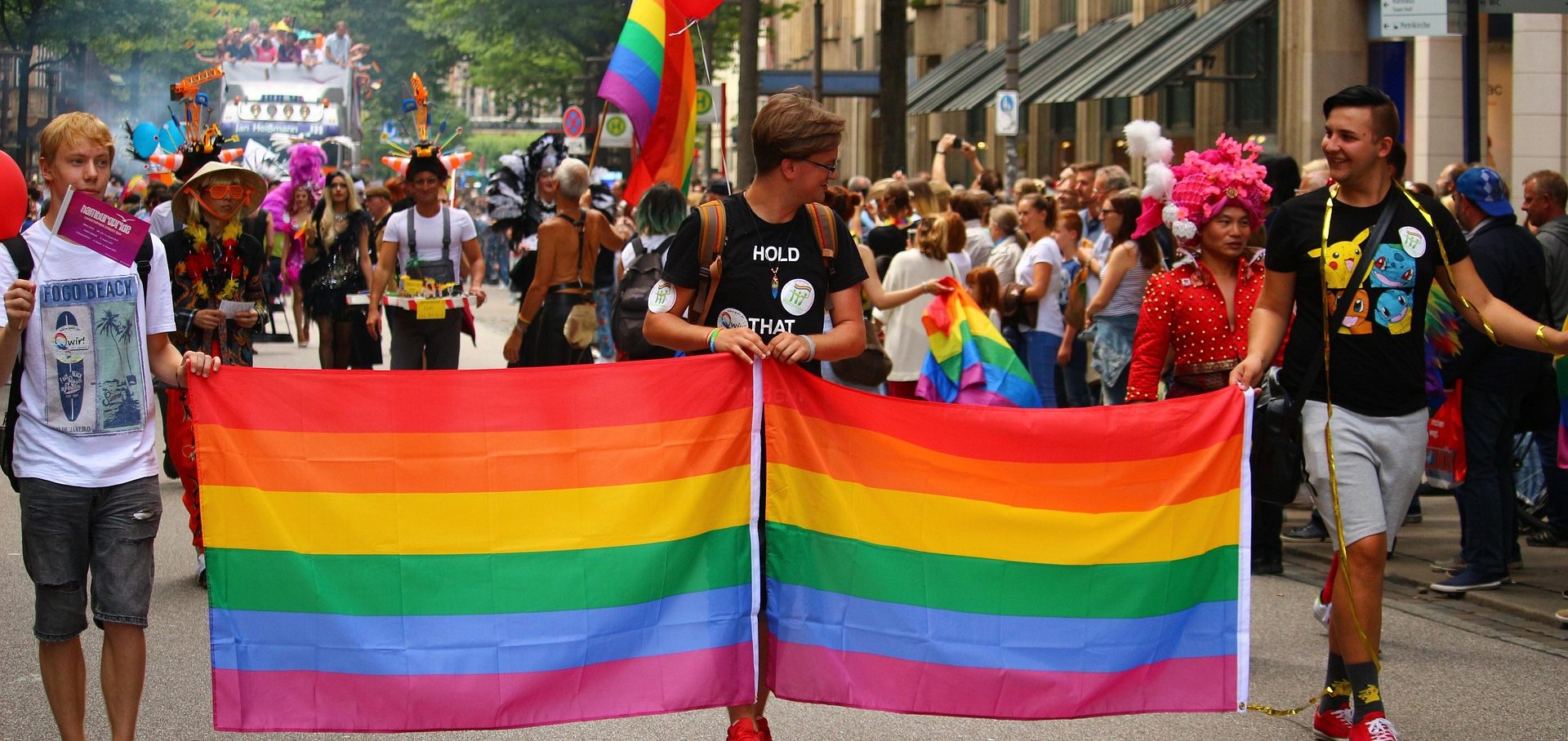 Deals best cruise lines Pride parade with participants holding a large rainbow flag, celebrating diversity and inclusion.