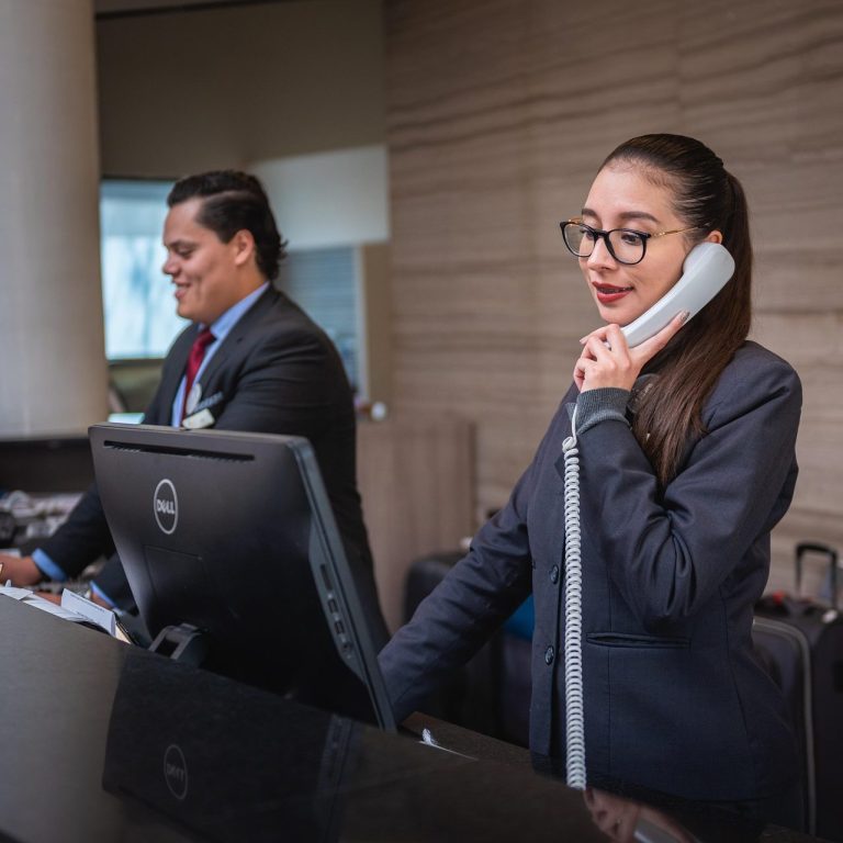 Traveler checking into hotel with luggage at front desk in sunny lobby